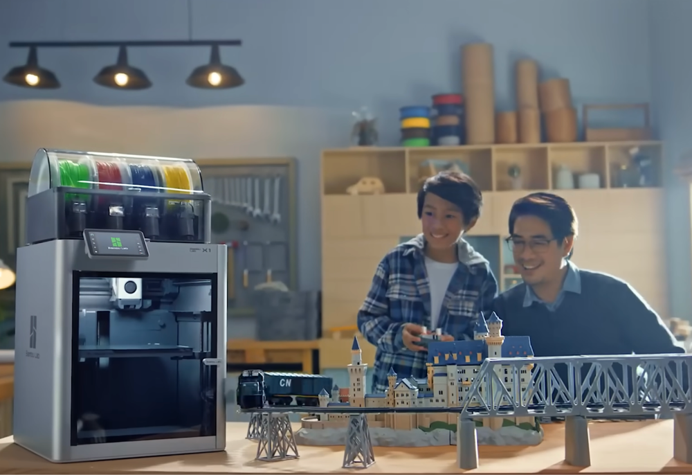 3D printer with colorful filaments and people working on architectural model prints